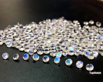 May include: A large pile of iridescent white gemstone beads, with a few smaller beads scattered around the pile. The beads are round and have a smooth, polished finish.