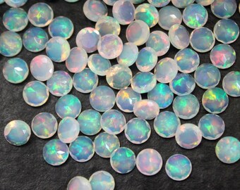 Pode incluir: Uma coleção de cabochões de opala branca iridescente, cada um com um padrão único de cor e luz.