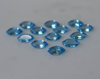 May include: A group of 13 marquise-shaped, light blue topaz gemstones. The gemstones are faceted and have a brilliant shine.