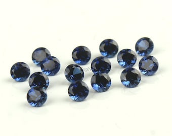 May include: A collection of 14 round, dark blue gemstones. The gemstones are faceted and have a shiny, polished finish.