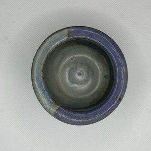 May include: A small, round ceramic bowl with a light blue glaze on the inside and a darker blue glaze on the outside.