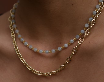 Könnte beinhalten: Eine mehrlagige Halskette mit einer goldenen Kette und einer Reihe hellblauer Perlen.