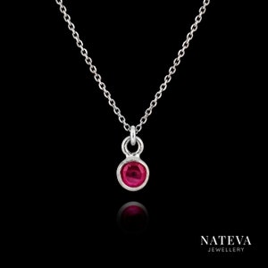 Può includere: Una collana con catena d'argento con un piccolo ciondolo con una pietra preziosa rotonda di colore rosso.