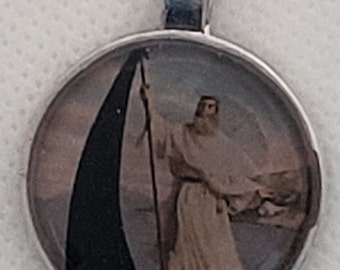 Può includere: Un ciondolo d'argento con un inserto di vetro rotondo che presenta un dipinto di una persona con una tunica bianca che tiene una bandiera nera.