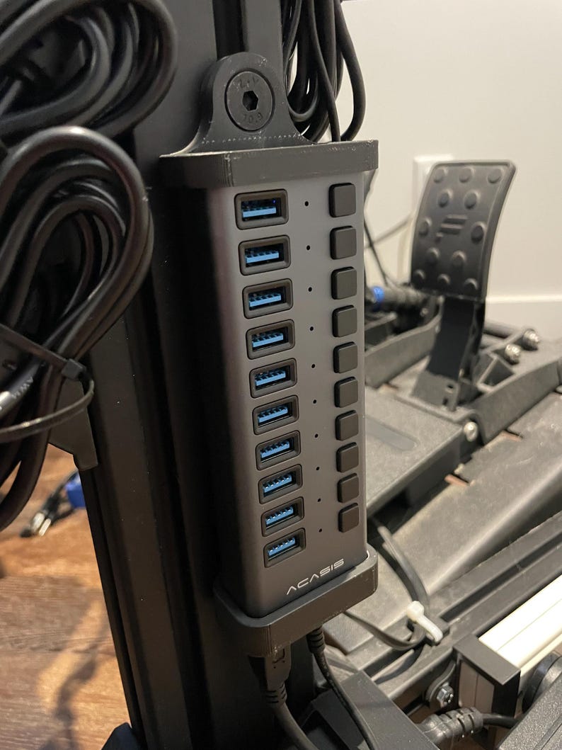 May include: A black USB hub with 7 blue USB ports and 7 black buttons. The hub is mounted on a black metal stand. The brand name "ACASIS" is printed on the hub.