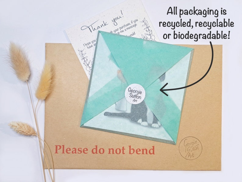 Peut inclure: Une enveloppe en papier brun avec une carte envelopp&eacute;e de papier de soie turquoise &agrave; l'int&eacute;rieur. La carte pr&eacute;sente une illustration en noir et blanc d'un chat. L'enveloppe porte l'inscription "Veuillez ne pas plier" imprim&eacute;e dessus. Le papier de soie porte l'inscription "Georgie Sutton Art" imprim&eacute;e dessus. La carte porte l'inscription "Merci !" imprim&eacute;e dessus. L'enveloppe a un petit autocollant avec le texte "Georgie Sutton Art" imprim&eacute; dessus. Le texte "Tous les emballages sont recycl&eacute;s, recyclables ou biod&eacute;gradables !" est &eacute;crit dans une bulle de dialogue au-dessus de l'enveloppe.