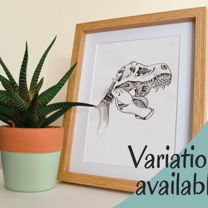 Puede incluir: Ilustraci&oacute;n en blanco y negro enmarcada de un cr&aacute;neo de Tyrannosaurus Rex. La obra de arte est&aacute; en un marco de madera clara con un passe-partout blanco. A la izquierda del marco hay una planta suculenta en maceta de dos tonos. El texto en la imagen dice "Variaciones disponibles".