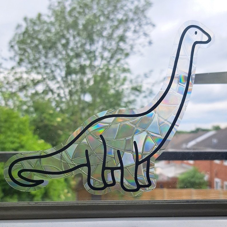 Pode incluir: Um desenho de linha preta de um dinossauro com um padr&atilde;o iridescente, semelhante a um mosaico. O dinossauro est&aacute; olhando para a direita e tem um pesco&ccedil;o e uma cauda longos.