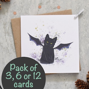 Peut inclure: Un chat noir avec des ailes violettes est assis sur un fond blanc avec des &eacute;claboussures violettes et vertes. Le texte "Pack of 3, 6 or 12 cards" est sous le chat.