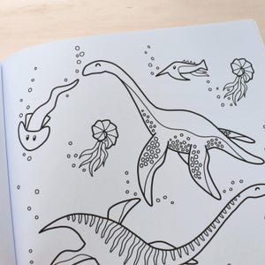 Pu&ograve; includere: Un disegno in bianco e nero di un plesiosauro, un rettile marino preistorico, che nuota nell'oceano. Il plesiosauro ha un collo lungo e quattro pinne. Nell'immagine ci sono anche disegni di meduse, un pesce e bolle.