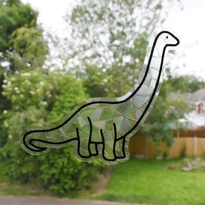 Pode incluir: Um contorno preto e branco de um dinossauro com um padr&atilde;o iridescente, semelhante a um mosaico. O dinossauro est&aacute; virado para a direita e tem um pesco&ccedil;o e uma cauda longos.