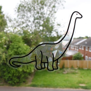 Pode incluir: Um contorno preto e branco de um dinossauro com um padr&atilde;o iridescente de mosaico. O dinossauro est&aacute; virado para a direita e tem um pesco&ccedil;o comprido.