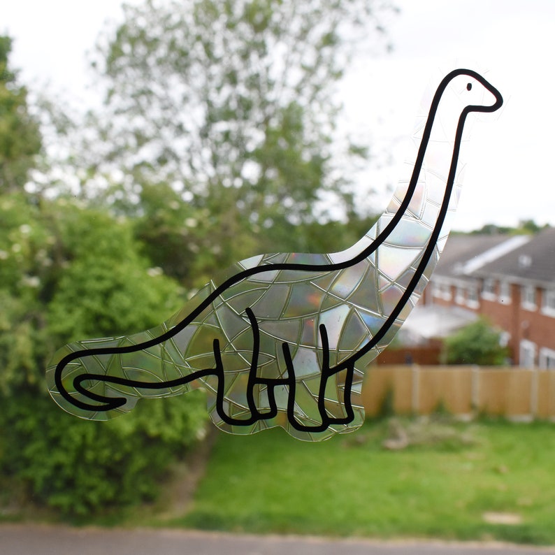 Pode incluir: Um contorno preto e branco de um dinossauro com um padr&atilde;o iridescente de mosaico. O dinossauro est&aacute; virado para a direita e tem um pesco&ccedil;o comprido.