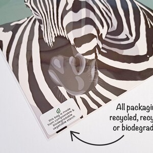 Puede incluir: Primer plano de una ilustraci&oacute;n de cebra con rayas blancas y negras. La imagen est&aacute; en una bolsa de pl&aacute;stico transparente con una pegatina que dice "esta bolsa est&aacute; hecha de almid&oacute;n vegetal compostable y biodegradable". El texto del embalaje dice "&iexcl;Todos los embalajes son reciclados, reciclables o biodegradables!"