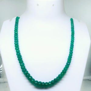 Puede incluir: Un collar de cuentas de piedras preciosas verdes. El collar está hecho de cuentas redondas y facetadas que están enhebradas en un cordón delgado. El collar mide aproximadamente 45 cm de largo.