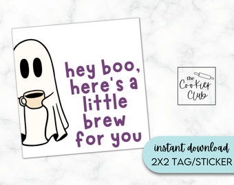 Può includere: Un fantasma bianco che tiene una tazza di caffè con il testo "hey boo, here's a little brew for you" in lettere viola. Il testo "the Cookier Club" è in lettere nere con un'icona di mattarello.