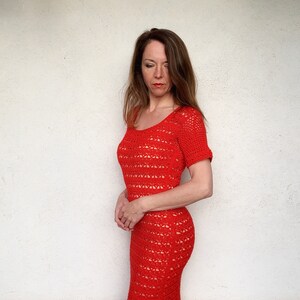 Puede incluir: Un vestido rojo de crochet con cuello redondo y mangas cortas. El vestido est&aacute; hecho de una tela ligera y transpirable y tiene un corte holgado y fluido.
