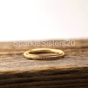 May include: Two gold-colored rings stacked on top of each other on a wooden surface.