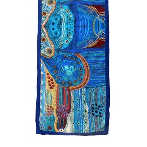 May include: A blue and orange patterned table runner with a dark blue border. The pattern features abstract shapes and dots.