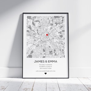 Puede incluir: Impresión enmarcada en blanco y negro de un mapa con un marcador de corazón rojo. La impresión incluye los nombres "JAMES & EMMA", detalles de la ubicación y la fecha "25 DE AGOSTO DE 2025". También se incluye el texto "LIFE IS AN ADVENTURE WITH YOU".