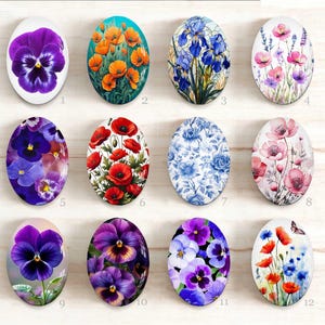 Peut inclure: Un ensemble de douze cabochons en verre ovales présentant des motifs floraux. Les images incluent des pensées violettes, des coquelicots orange, des iris bleus, de la lavande, des coquelicots rouges, des motifs floraux bleu et blanc, des fleurs roses et un papillon avec des fleurs sauvages.