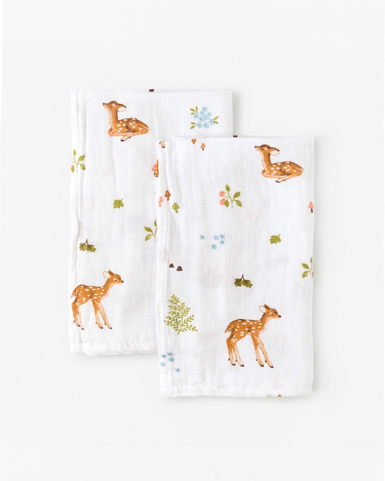 May include: Two white muslin baby burp cloths with a repeating pattern of brown deer, green leaves, and pink and blue flowers.