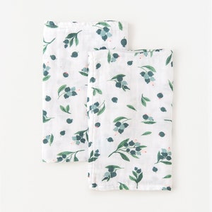 May include: Two white muslin baby burp cloths with a green and blue blueberry print.