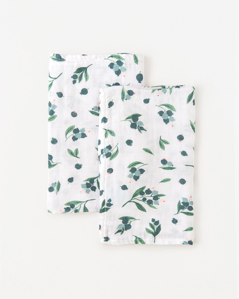 May include: Two white muslin baby burp cloths with a green and blue blueberry print.