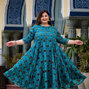 May include: A teal blue dress with a geometric pattern and a round neckline. The dress has a flared skirt and three-quarter sleeves.