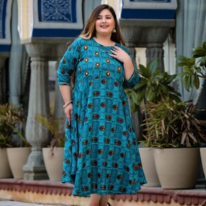 May include: A teal blue maxi dress with a geometric pattern of brown squares and circles. The dress has a round neckline and three-quarter sleeves.