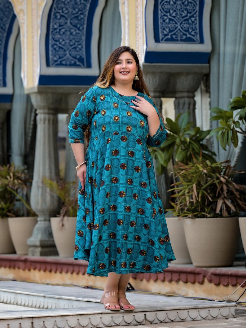 May include: A teal blue maxi dress with a geometric pattern of brown squares and circles. The dress has a round neckline and three-quarter sleeves.