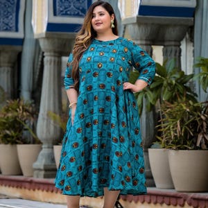 May include: A teal blue maxi dress with a geometric pattern of brown and gold circles. The dress has a round neckline and three-quarter sleeves.