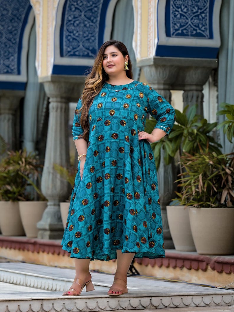 May include: A teal blue maxi dress with a geometric pattern of brown and gold circles. The dress has a round neckline and three-quarter sleeves.