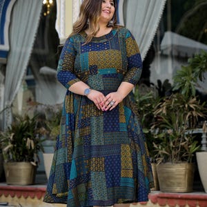 May include: A blue, green, and gold patterned dress with a 3/4 sleeve and a flared skirt. The dress has a round neckline and is decorated with small gold beads.