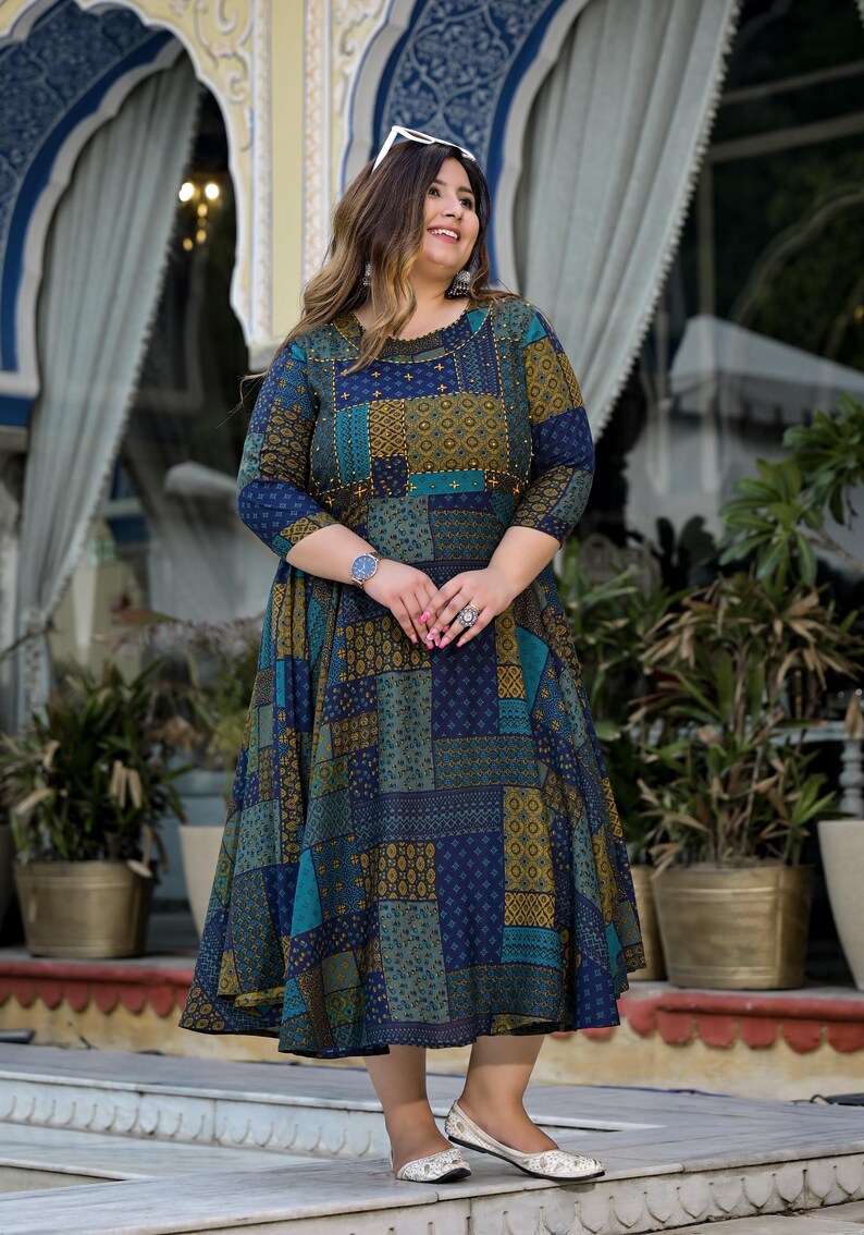 May include: A blue, green, and gold patterned dress with a 3/4 sleeve and a flared skirt. The dress has a round neckline and is decorated with small gold beads.