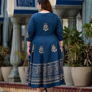 May include: A navy blue maxi dress with a gold floral print. The dress has a round neckline and three-quarter sleeves. The dress is made of a soft, comfortable fabric and has a flowy silhouette.