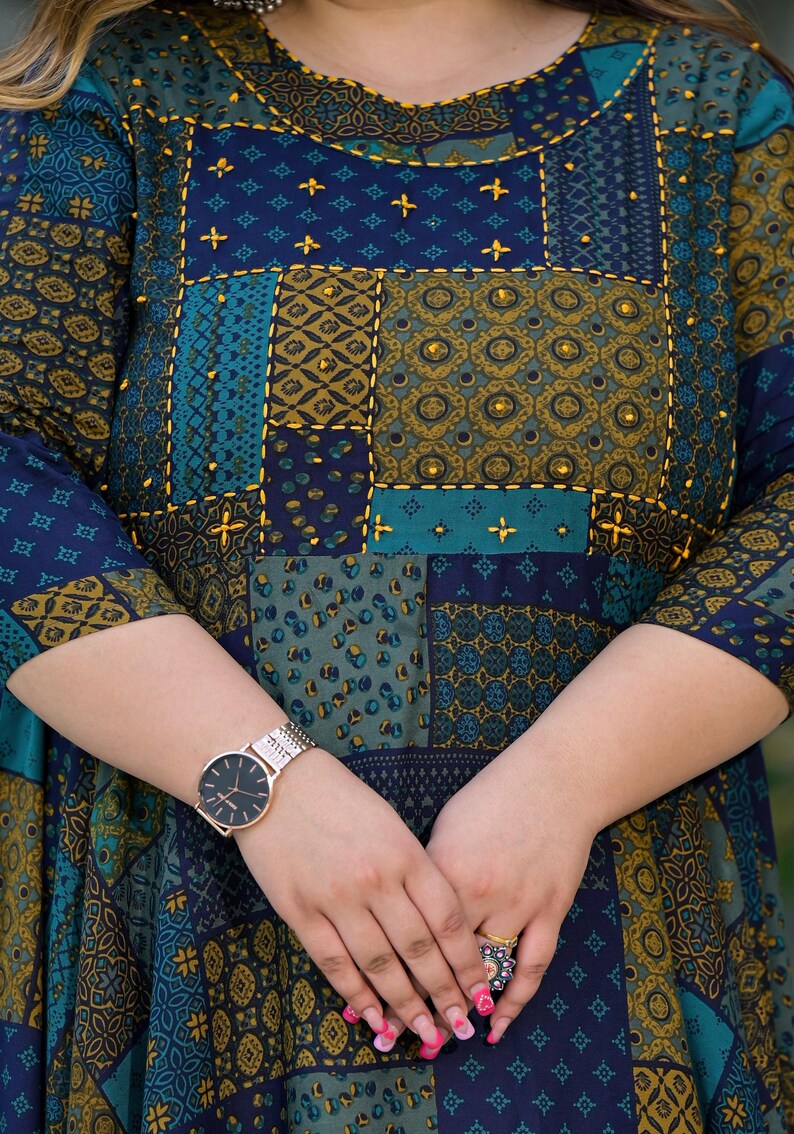 May include: A blue and green patterned dress with gold embroidery and a gold watch on the left wrist.