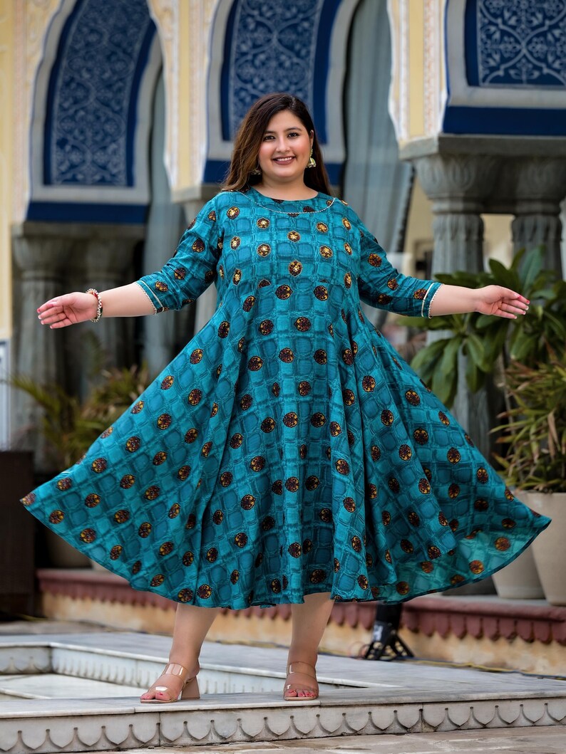May include: A teal blue dress with a geometric pattern and a round neckline. The dress has a flared skirt and three-quarter sleeves.