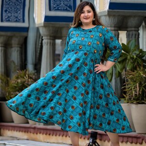 May include: A teal blue maxi dress with a geometric pattern and 3/4 sleeves. The dress has a round neckline and a flowing skirt.