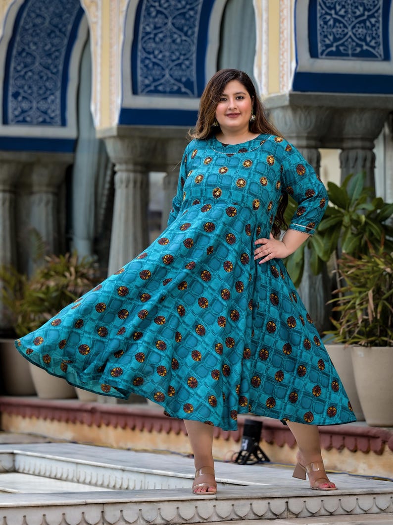 May include: A teal blue maxi dress with a geometric pattern and 3/4 sleeves. The dress has a round neckline and a flowing skirt.