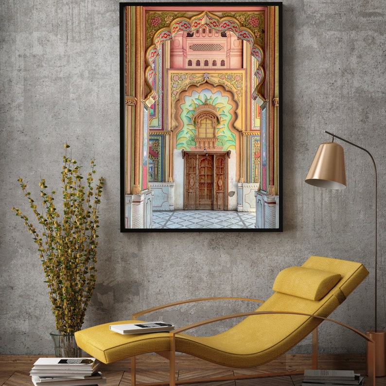 May include: A framed photograph of a colorful, ornate doorway with a wooden door. The doorway is decorated with intricate carvings and patterns in shades of pink, green, yellow, and blue. The door is made of wood and has a carved design.