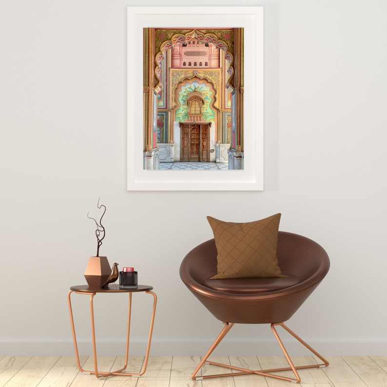 May include: A framed photograph of a colorful, ornate doorway with a wooden door in a pink, green, and gold building. The doorway is framed by arches and intricate details.