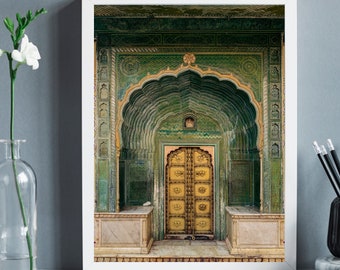 Op de afbeelding: Een grote, sierlijke deuropening met een groene en gouden boogvormige ingang. De deur is van hout en heeft ingewikkelde houtsnijwerk. De deuropening wordt omlijst door een witte muur.
