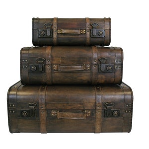 May include: Three vintage-style brown leather suitcases stacked on top of each other. The suitcases have metal clasps and handles.