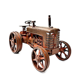 May include: A rusty red metal toy tractor with a detailed engine and wheels. The tractor has a brown wooden seat and a black metal steering wheel.