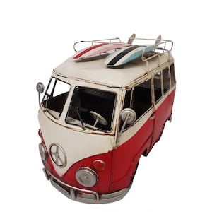 May include: A red and white vintage-style camper van with a surfboard on the roof. The van has a peace sign on the front and a rusty, distressed look.