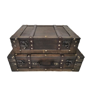 May include: Two stacked, dark brown wooden trunks with metal hardware. The trunks have leather straps and handles, and are secured with metal latches and rivets. The trunks are rectangular and have a vintage aesthetic.