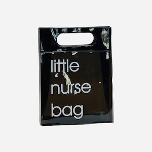Puede incluir: Una bolsa tote negra y brillante con una abertura rectangular para el asa en la parte superior. Las palabras "little nurse bag" están impresas en blanco, centradas en la parte delantera de la bolsa. La bolsa tiene forma rectangular.