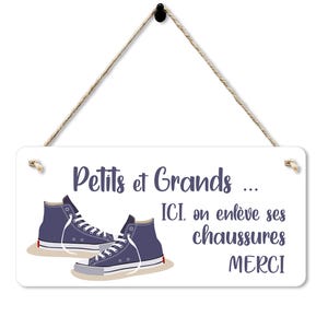 Könnte beinhalten: Weißes rechteckiges Schild mit dem Text "Petits et Grands... ICI, on enlève ses chaussures MERCI" in Lila. Das Schild zeigt ein Paar blaue High-Top-Sneaker. Das Schild ist an einem Naturseil aufgehängt.