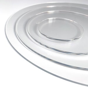 Peut inclure: Ensemble de quatre assiettes circulaires transparentes en acrylique de tailles différentes, imbriquées les unes dans les autres. Les assiettes transparentes laissent apparaître le fond blanc. Les bords des assiettes sont lisses et légèrement arrondis.
